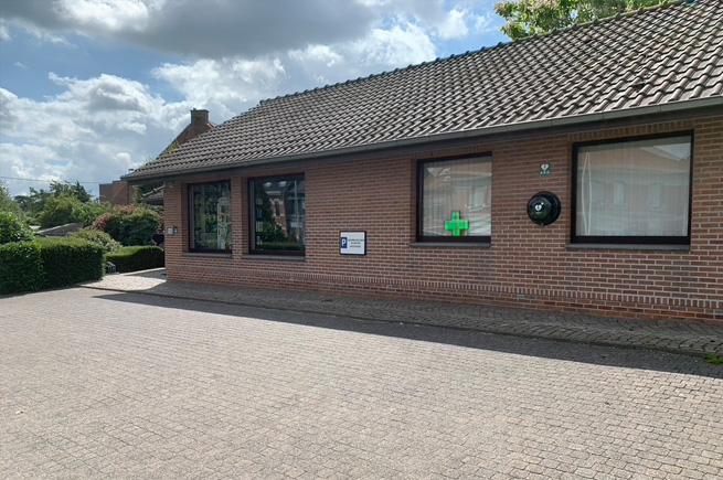 De bakstenen gevel van Apotheek Bosman met het groene apotheekkruis